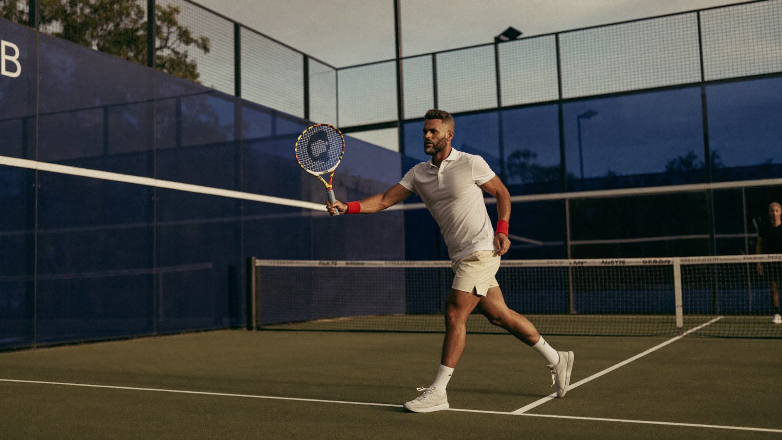 Padel player in their forties stretching at the back of the court